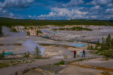 YELLOWSTONE, MONTANA, USA MAY 24, 2018: Above view of people walking in the boardwalk among pools and geysers, porcelain basin of Norris Geyser Basin, Yellowstone National Park, Wyomingのeditorial素材