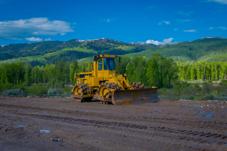YELLOWSTONE NATIONAL PARK, WYOMING, USA - JUNE 07, 2018: Road construction equipment parked in a construction zone. Roadwork in Yellowstone National Park in gorgeous sunny day and blue sky backgroundのeditorial素材