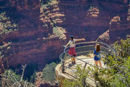 Grand Canyon,Arizona USA, JUNE, 14, 2018: Two women hiker is standing on a steep cliff taking in the amazing view over famous Grand Canyon on a beautiful sunny day with blue sky in summer in Arizonaのeditorial素材