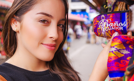 Close up of smiling woman holding in her hands an Indian handmade wallet at a craft store in the Passage Craft in the downtown of the city of Banosの写真素材