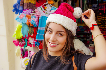 Close up of woman wearing a christmast hat in front of souvenir store in the Passage Craft in the downtown of the city of Banosの写真素材