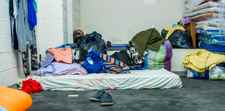QUITO, ECUADOR, AUGUST 21, 2018: Pile of colorful clothes, bags and accessories in the ground of a room inside of a refuge center for people that escape from their country Venezuelaのeditorial素材