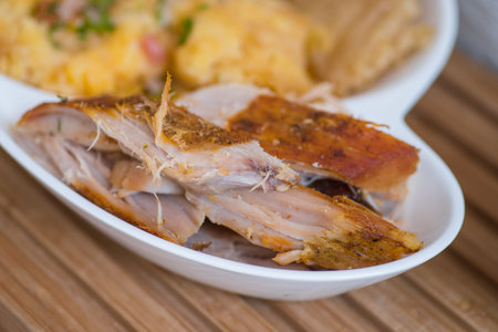 Close up of typical Andean food hornado inside of a white plate with mashed potatoes with salad in a...