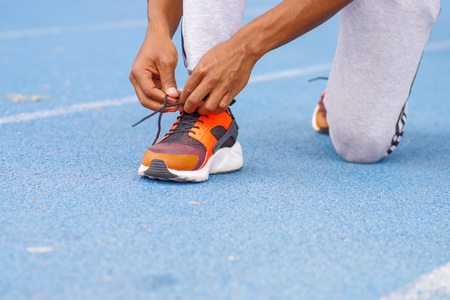Close up of selective focus of hands and legs of young black athlete man tying running shoes in the park outdoor, wellness and sport concepts in the city of Quito Ecuador.の写真素材