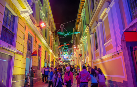 QUITO, ECUADOR- AUGUST, 15, 2018: Unidentified group of blurred people walking in a tight street during a spectacle of festival of lights projected on the walls with some illuminated figures in Quitoのeditorial素材