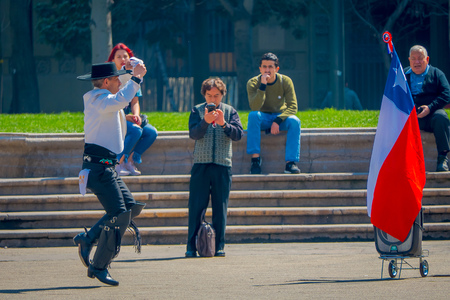 SANTIAGO, CHILE - SEPTEMBER 13, 2018: Outdoor view of unidentified man wearing boots, white t-shirt and black pants dancing in Armas square in front of a Chilean flag in Santiago, Chileのeditorial素材