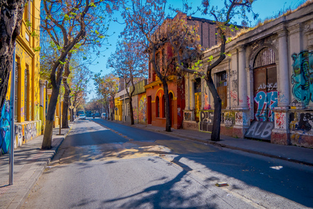 SANTIAGO, CHILE - SEPTEMBER 13, 2018: Cars circulating in a stoned pavement under trees at one side of the street in the Barrio Yungay in Santiago, capital of Chileのeditorial素材