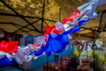 SANTIAGO, CHILE - SEPTEMBER 13, 2018: Outdoor view of white, red and blue paper coor hanging representating the colors of the Chilean flag in a blurred background in the city of Santiago of Chileのeditorial素材