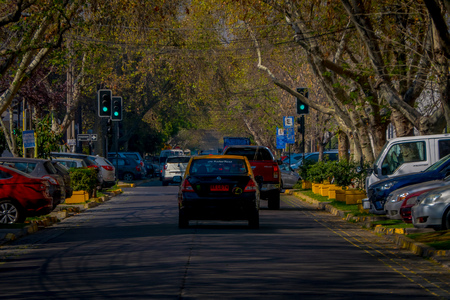 SANTIAGO, CHILE - SEPTEMBER 13, 2018: Outdoor view of some cars circulating in the streets with a greet traffict light, surrounding of trees at each side of the sidewalk in Santiagoのeditorial素材