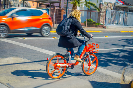 SANTIAGO, CHILE - SEPTEMBER 13, 2018: Unidentified woman biking her rental bike in the city during gorgeous beautiful sunny day in dowtown of the city at Santiagoのeditorial素材