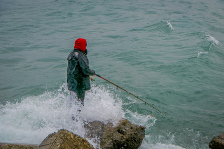 Unidentified fisherman standing in a rock with a fishing rod on chilean patagonia in Chile.の写真素材