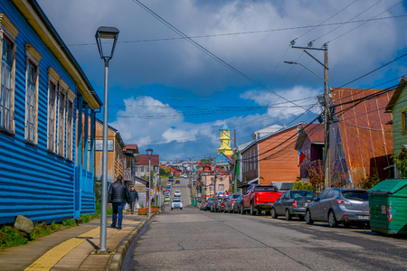 CHILOE, CHILE - SEPTEMBER, 27, 2018: Outdoor view of some cars parking at one side of the road cose to many wooden buildings in Chiloe island in a gorgeous blue sky in Chileのeditorial素材