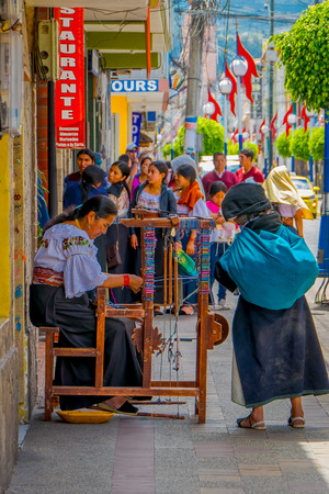 OTAVALO, ECUADOR, NOVEMBER 06, 2018: Unidentified woman with a turquoise bag and watching the handmade bracelet in the sidewalk in the city of Otavaloのeditorial素材