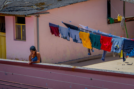 OTAVALO, ECUADOR, NOVEMBER 06, 2018: Outdoor view of unidentified woman close to a clothes drying in the sun in Otavaloのeditorial素材