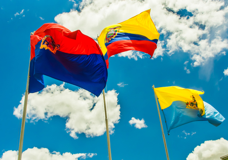 Latacunga, Ecuador, September, 28, 2018: Outdoor view of three flags waving in a gorgeous blue sky background with some clouds in the city of Latacungaのeditorial素材