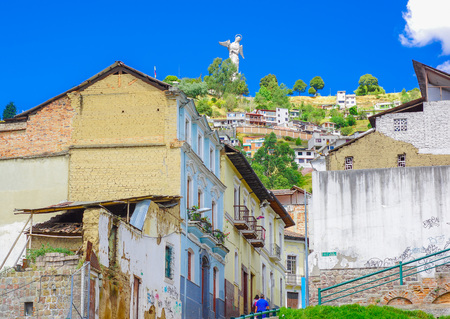 QUITO, ECUADOR AUGUST, 28, 2018: Outdoor view of colonial buildings houses located in the city of Quito with the statue of Virgin of Panecillo in the background in gorgeous sunny day with blue skyのeditorial素材
