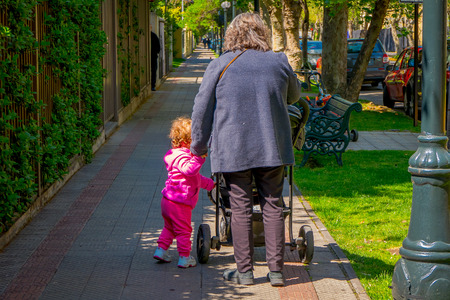 SANTIAGO, CHILE - SEPTEMBER 13, 2018: Outdoor view of woman with a baby carriage walking in a park locate din the city of Santiago of Chile during gorgeous beautiful sunny dayのeditorial素材