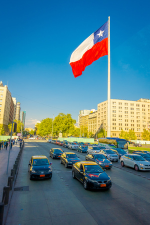 SANTIAGO, CHILE - SEPTEMBER 13, 2018: Outdoor view of people walking in the streets, close to the square of Plaza de Armas located in Santiago de Chile with ahuge Chilean flag wavingのeditorial素材