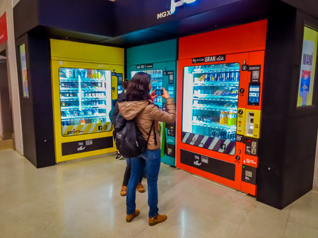 SANTIAGO, CHILE - OCTOBER 09, 2018: Unidentified woman taking a picture in front of a coin machine of juice and snacks located in the Sweeden station line 6 in Metro station in Santiagoのeditorial素材