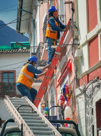Quito, ECUADOR - 02 October 2019: Electricians are climbing on electric poles to install and repair power lines.のeditorial素材