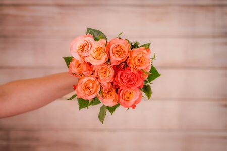 Women hand holding a bouquet of peach Shimmer roses variety, studio shot.の写真素材