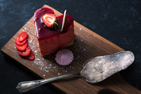 Heart Cake picture . Lovely delicious heart cake. A red colored cheesecake on a plate and a wooden table.の写真素材