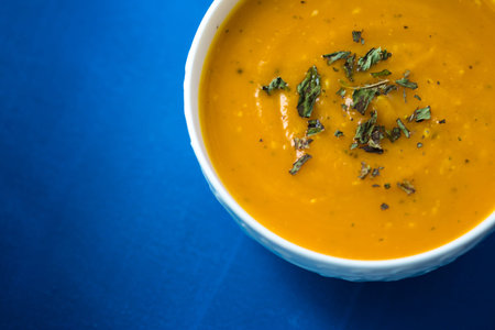 Pumpkin cream soup. Fresh soup with herbs on a background, Autumn concept. Tasty healthy food