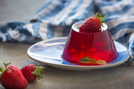 Photo of fruit jelly with fresh strawberry. Healthy food. Strawberry jelly on white plate. Summer dessert with fruit jelly and fresh strawberryの写真素材