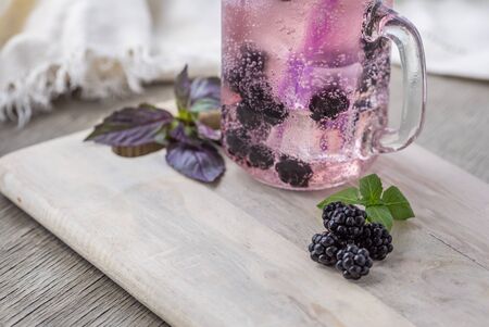 Home fizzy drink with ice and blackberry on a light background, selective focus. Photo of home made refreshing beverage.の写真素材