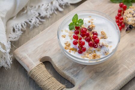 Bowl of fresh red currant and yogurt. Photo of breakfast bowl with farm fresh currant served on a wooden boardの写真素材