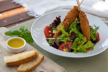 Fried chicken on wooden skewers with vegetable salad and sauce. Spring picnic,,. Delicious lunch. On light background.の写真素材