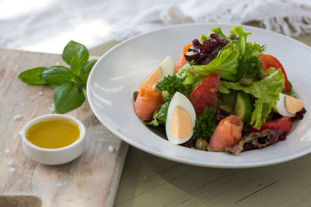 Vegetable salad with egg and salmon served with basil and topping sauce.の写真素材