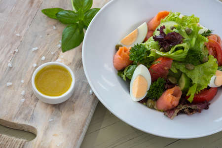 Vegetable salad with egg and salmon served with basil and topping sauce.の写真素材