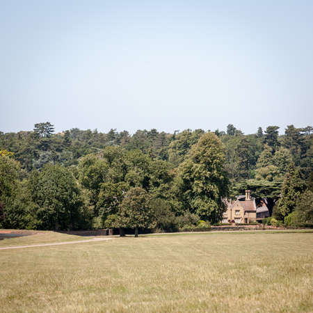 A traditional English country house surrounded by a forest and nestled in  a rural countryside setting on a bright summerのeditorial素材