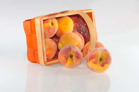 Peaches in a basket on a white background with reflectionの写真素材