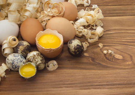 Chicken and quail eggs on wooden background.Broken and whole eggsの写真素材