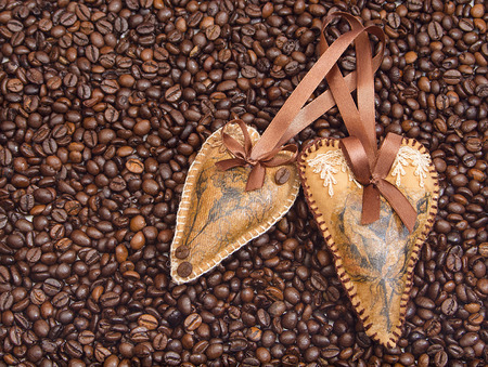 two decorated hearts with ribbons on a background coffee grainsの写真素材