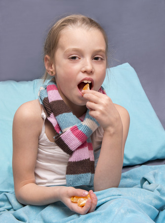 school-age child is recovering from an illness and eating vitaminsの写真素材