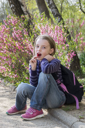 Happy little girl with lollipop outdoors in springの写真素材