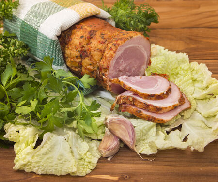Baked boiled pork with greenery and slices of of garlic on wooden deskの写真素材