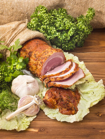 Baked boiled pork with greenery and slices of of garlic on wooden deskの写真素材
