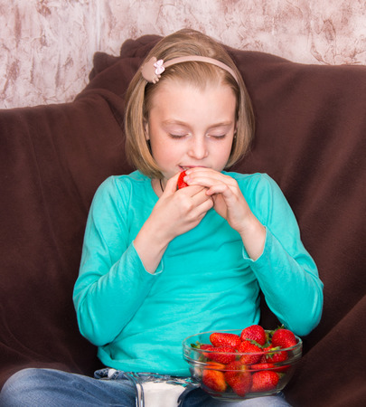 Little girl eating ripe strawberries with sugarの写真素材