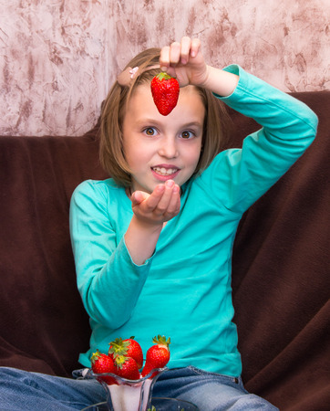 Little girl eating ripe strawberries with sugarの写真素材