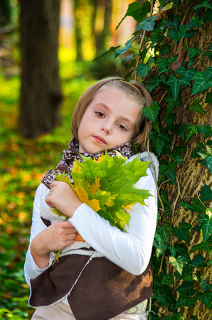Portrait  little girl with colored maple leaves in autumn park.の写真素材