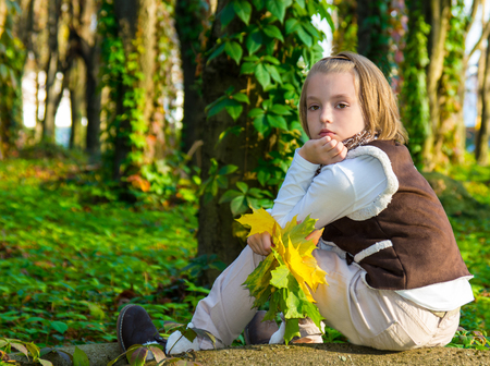 Portrait  little girl with colored maple leaves in autumn park.の写真素材