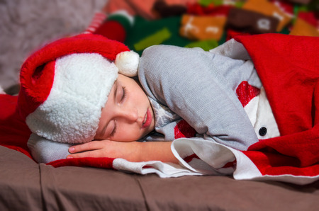 Sweet little girl sleeps in Santa caps on Christmas Eve.の写真素材