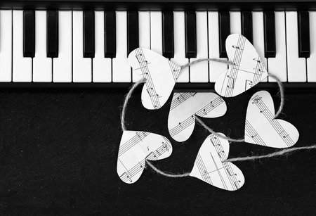 Piano keys and hearts of the music on a black background. I love music concept.の写真素材