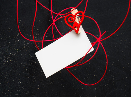 Blank card for text with clothespins heart on a black background . Symbol of love.の写真素材