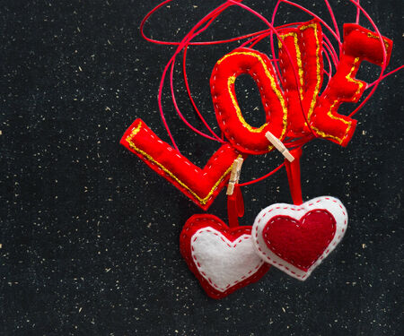 Two hearts and the word love made of fabric on a black background. Symbol of love.の写真素材
