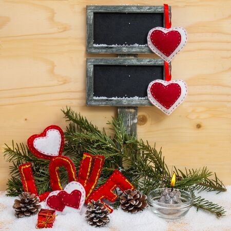 Hearts and the word love made of cloth with burning candle and a sign for text on wooden background. Symbol of love.の写真素材